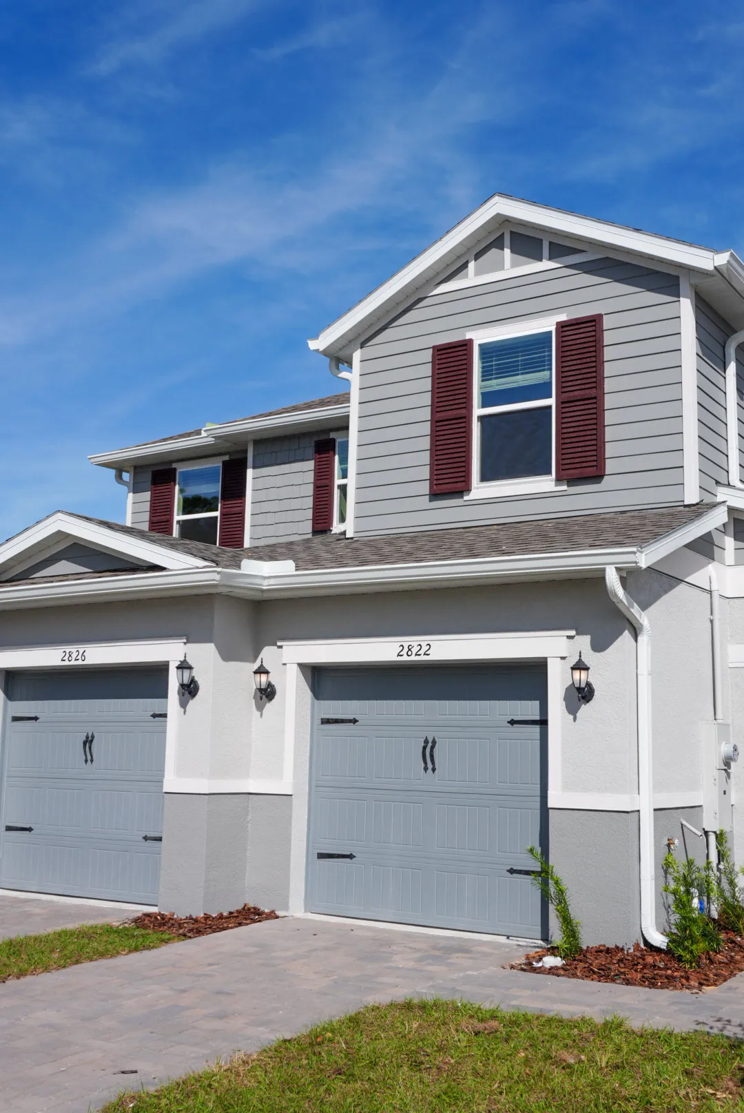 Two story Florida home with fresh gray exterior paint and red shutters