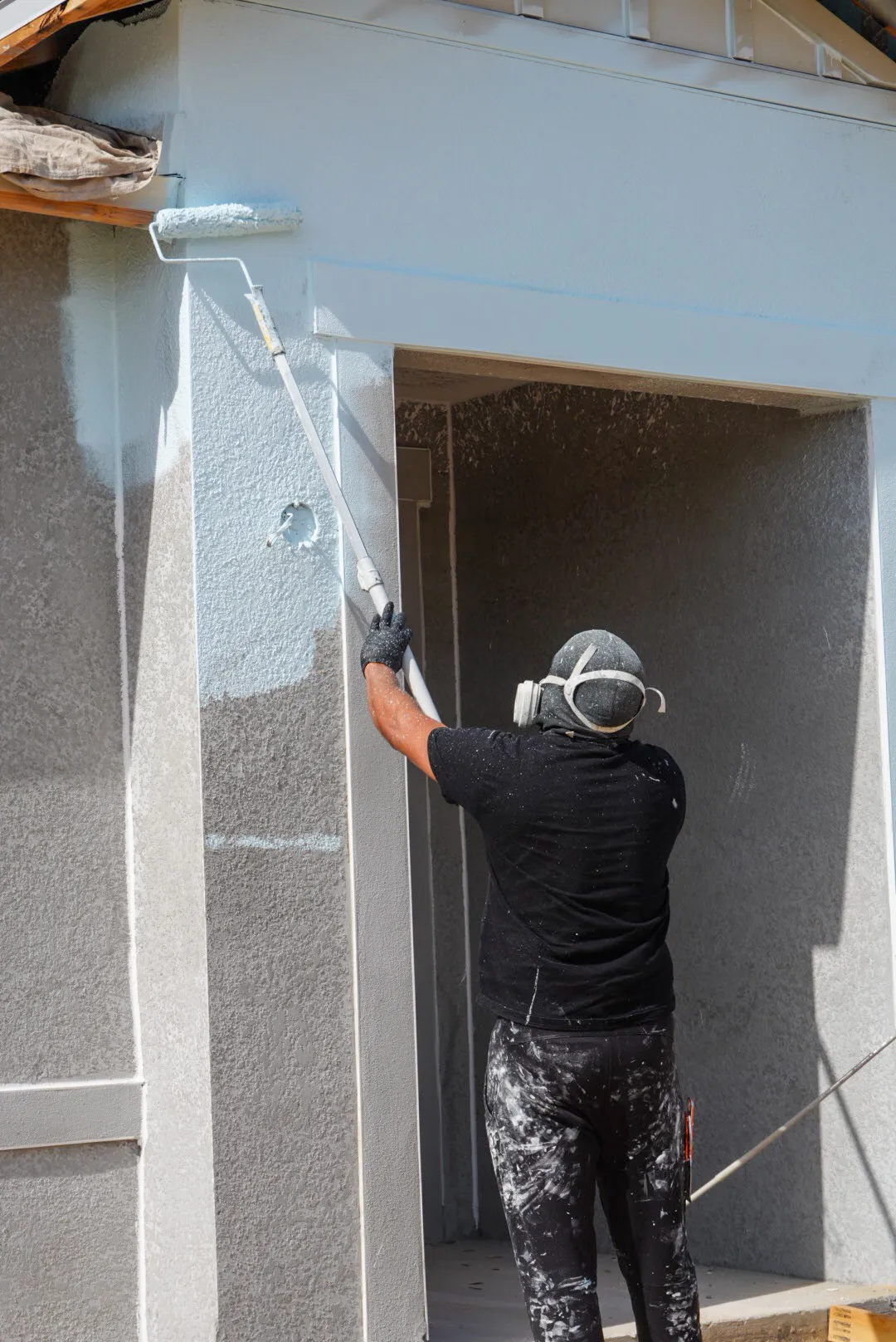 Glades Pro painter rolling paint on exterior stucco